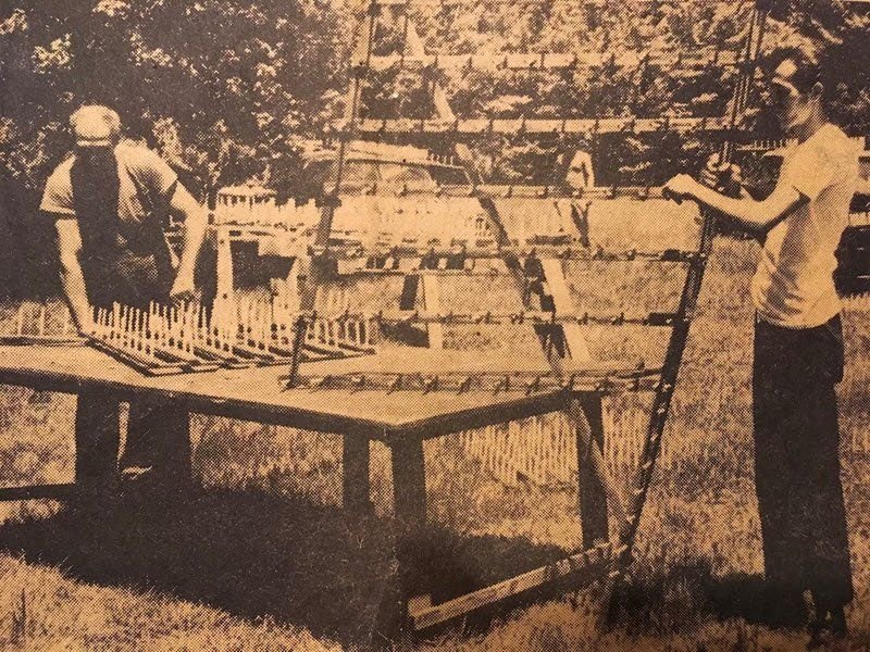 Two men assembling a wooden set-piece frame outdoors in a 1973 archival print